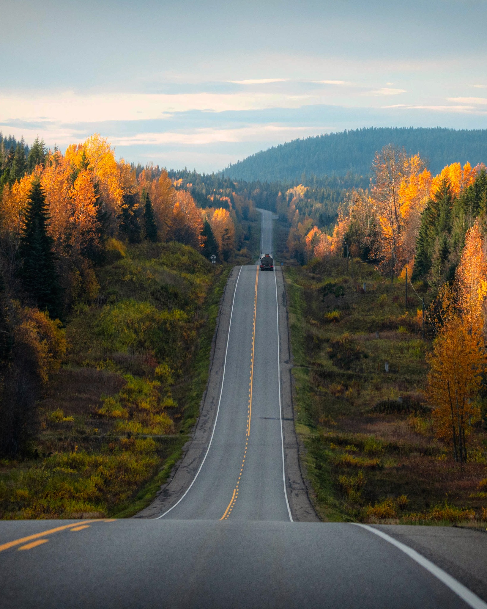 photo by maximilianruther caption reads: A few weeks ago, I went on a solo road trip down the Yellowhead Highway near Prince George. The fall scenery was stunning. 🍁🍂 I love this picture because it captures the highway's ups and downs, the vibrant fall colors, and the distant truck adding perspective. 📸 #FallRoadTrip #YellowheadHighway #AutumnJourney #ScenicDrive #princegeorgebc #canadahighway