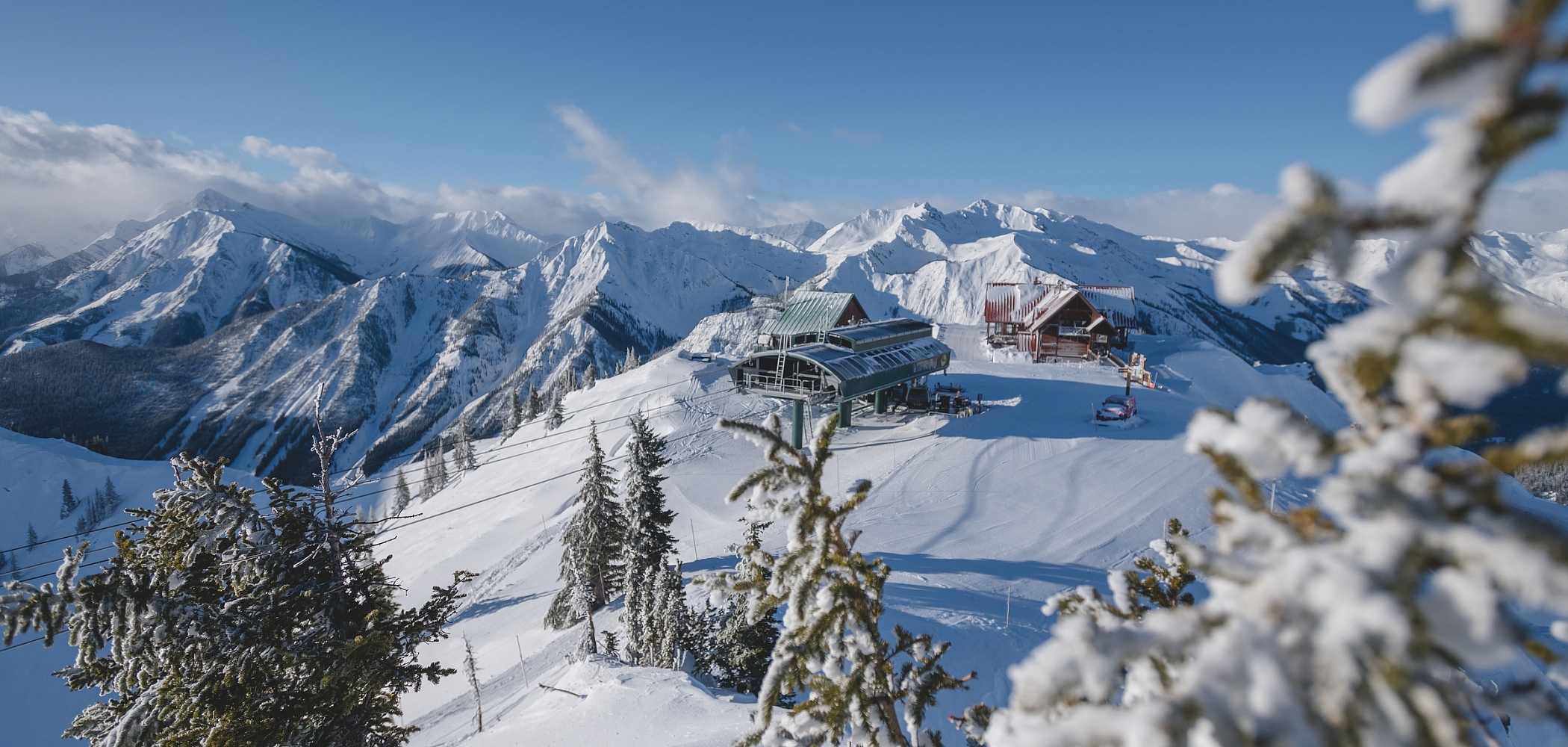 View through the snowy trees of the chairlift station at Kicking Horse Mountain Resort.